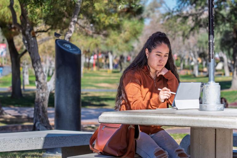 Student sitting outside and using their tablet. 